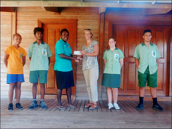 Standing in between the Student Council is Ms Chareen Simbe receive a cheque of $5,000 from Mrs. Barbara Vollrath of Woodford International School.