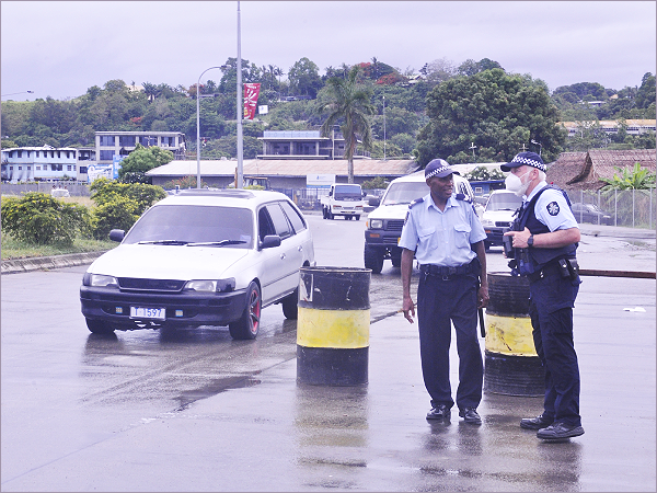 A RSIPF Police officer assisted by an AFP officer manning the Honiara City Council roundabout checkpoint on Monday.