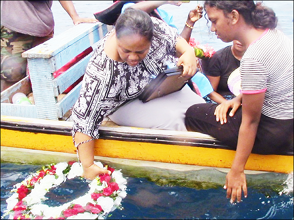 A family member laying a wreath in the ocean.