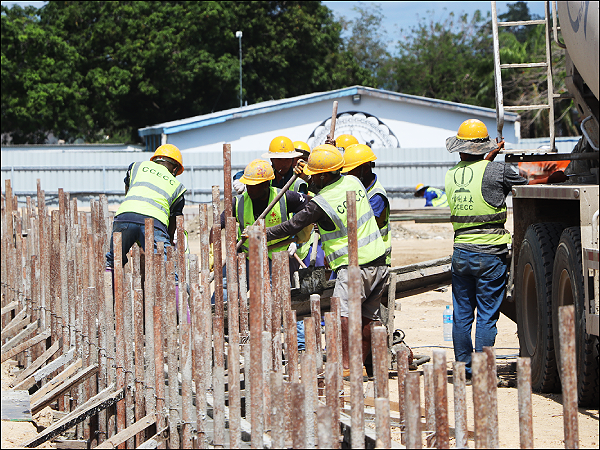 Local workers and CCECC engineers pour foundation concrete for the trial track and field.