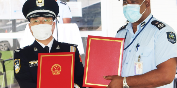 Commissioner Zhang of the China Police Liaison Team and Commissioner Mostyn Mangau of the RSIPF with the certificates of handover at the Rove Police Headquarters.