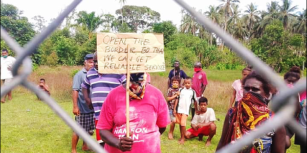 A woman holding up a placard to reopen the border. (Photo supplied)