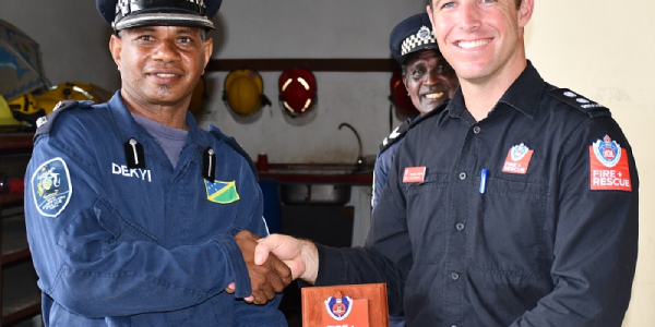 FRNSW Leading Firefighter, Jordan, presenting a gift to the RSIPF’s Fire and Rescue Services’ Dekyi.