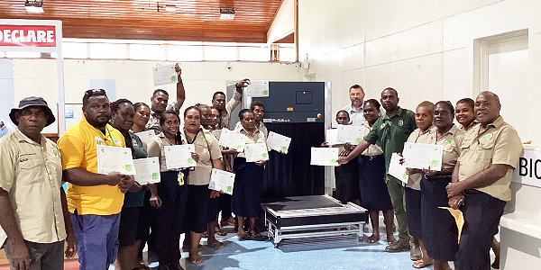 BSI Officers in a group photo with their Director Francis Tsatsia, first far right, Max Kolubalona, standing first on the left, is the National Facilitator for the Solomon Islands Biosecurity Development Program. At the back on the right is the Biosecurity X-ray certified Trainer, Drechsler Dave. They all posing with the New Airport X-ray Machine.
