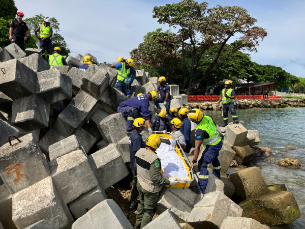 Rescuers doing stretcher passing of casualty through the rubble.