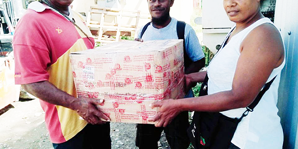 Ward 29 Development Committee Treasurer, Nester Totoramo (right) delivering a project to a project recipient. Photo by Solomon Lofana.