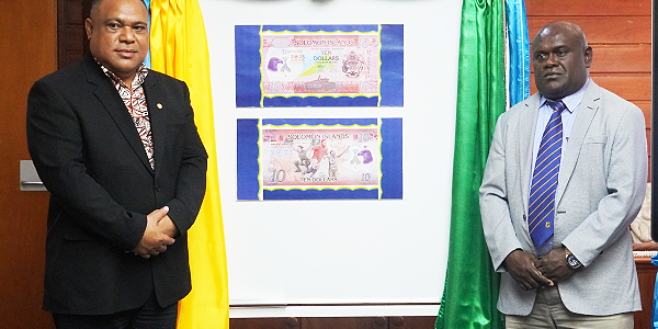 CBSI Governor Dr Forau (left) and the Minister of Finance & Treasury Harry Kuma unveiling the 17th Pacific Games commemorative polymer $10 note in a ceremony convened in the CBSI Boardroom.