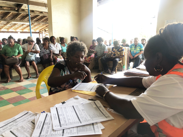 Gloretta Andersen (R) assists a lady in round 1 of registrations at All Saints Church, Central Honiara.