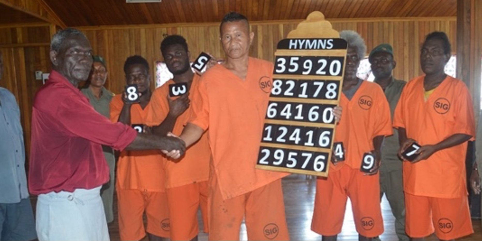 Pastor Siope receiving the hymnal board from one of the inmates