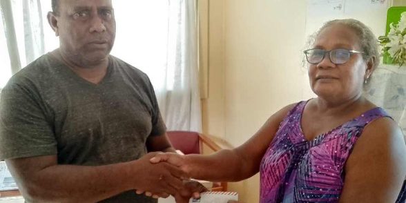 MPA Talu handing over the envelope of financial donation from Premier Asilaua to the Bibisu Unity Christian Life Centre AOG Church rep Elizabeth Matangani