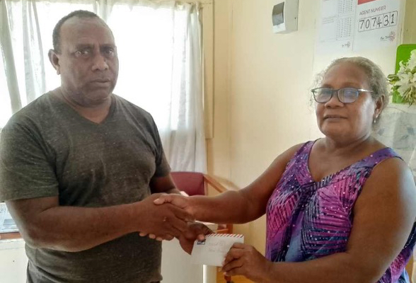 MPA Talu handing over the envelope of financial donation from Premier Asilaua to the Bibisu Unity Christian Life Centre AOG Church rep Elizabeth Matangani