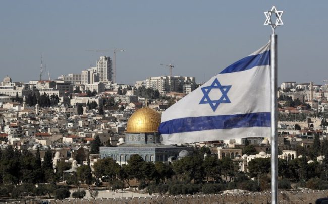 The Israeli flag flutters in front of the Old City of Jerusalem’s Dome of the Rock on December 1, 2017. (AFP Photo:Thomas)