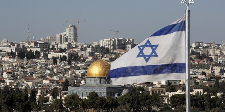 The Israeli flag flutters in front of the Old City of Jerusalem’s Dome of the Rock on December 1, 2017. (AFP Photo:Thomas)