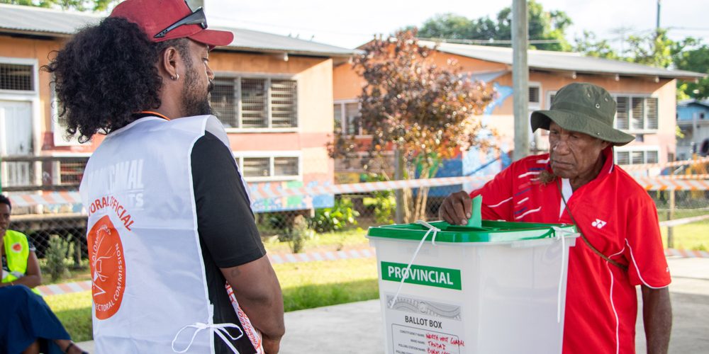 Ballot Box Guide officer watch as voter cast his ballot paper at Burns Creek polling station