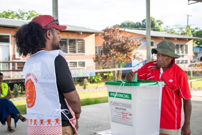 Ballot Box Guide officer watch as voter cast his ballot paper at Burns Creek polling station