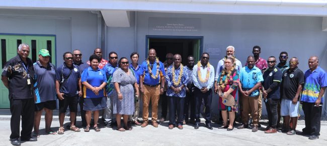 PM and PG 2023 Minister (centre) with Cabinet Ministers, and NHA, NOCSI, NSC and Sports Federation reps standing in front of the Sports Legacy House after the handover