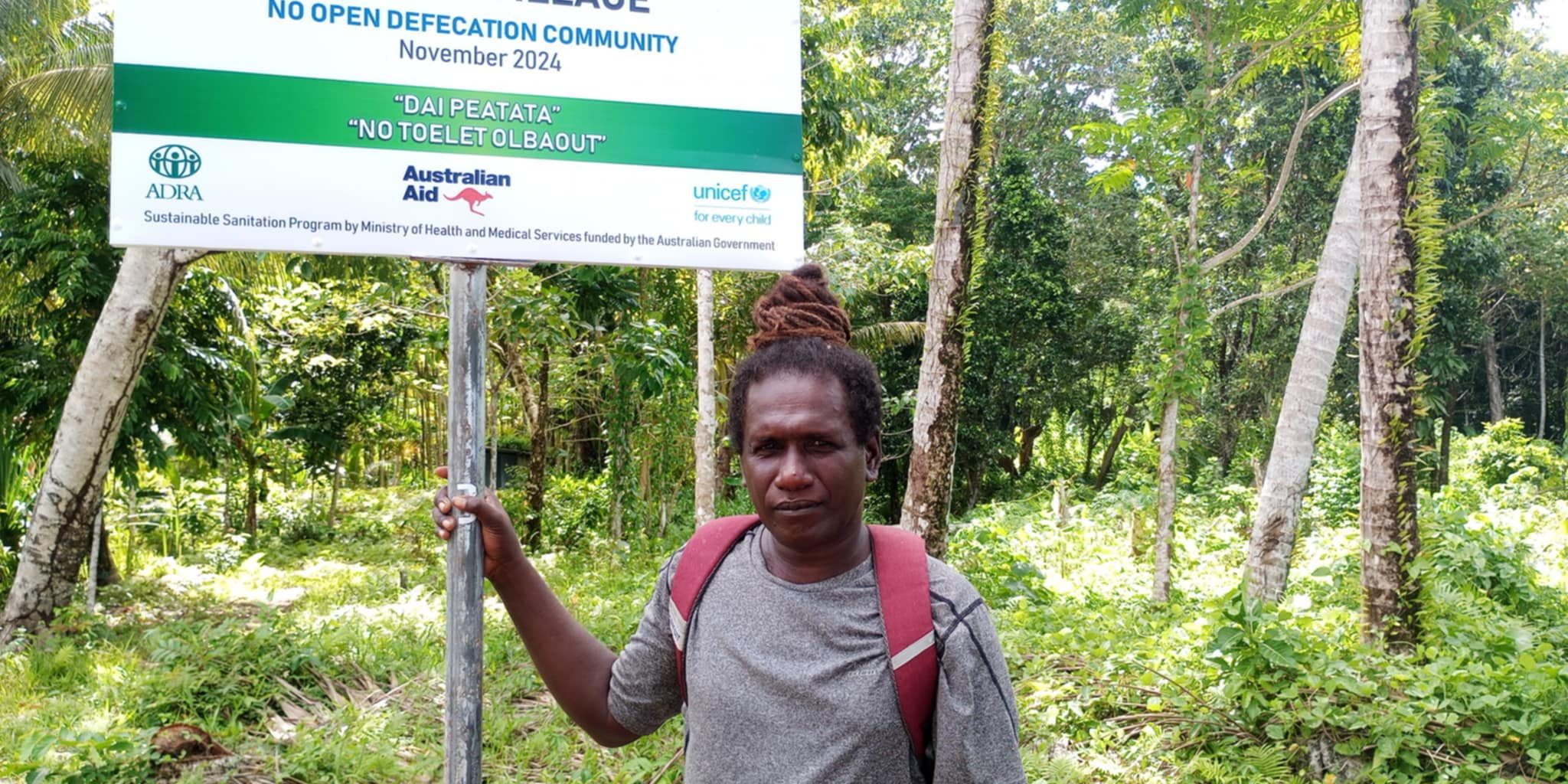 Chris Panakera taking photo Infront of signboard at his community in Rannogah.