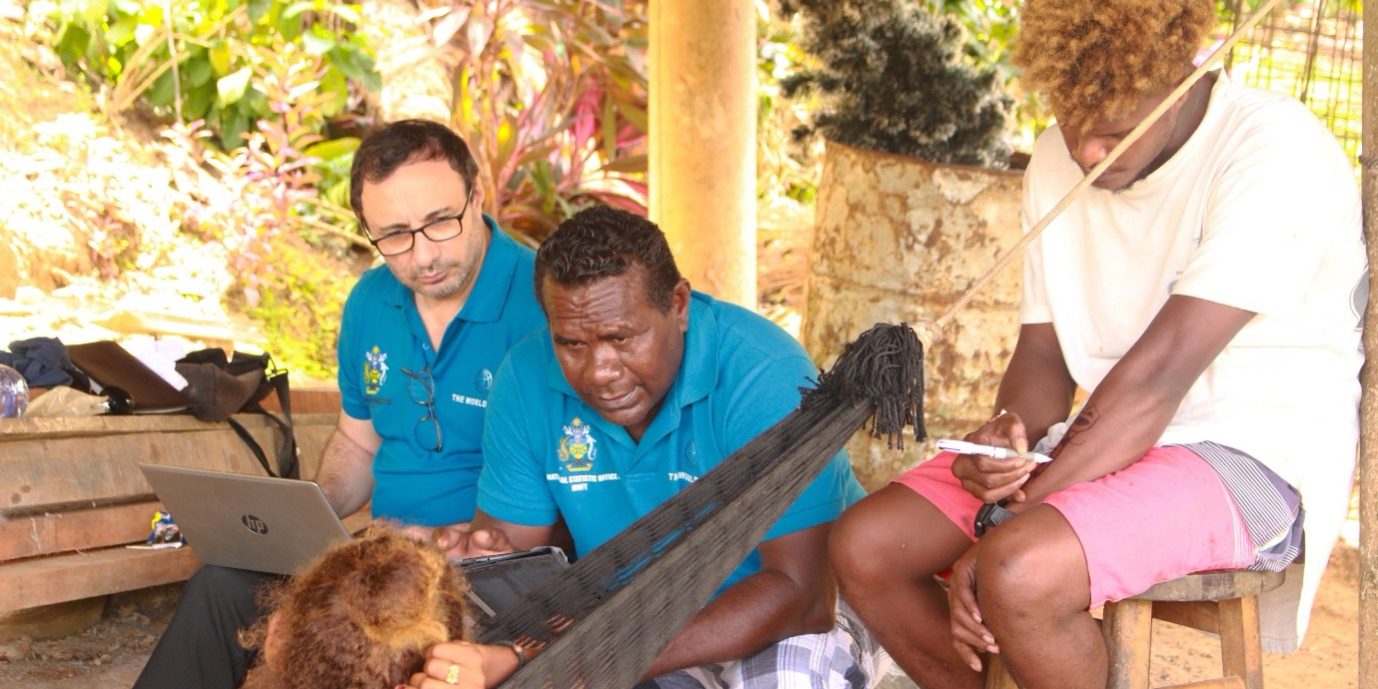 Enumerator Tony Ferris interviewing two household members while Statistics Resident Advisor Dr. Cengiz Ozkan looks on.