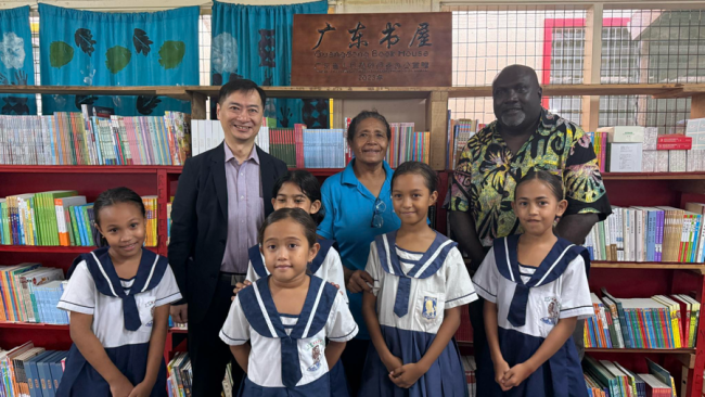 H.E, Weiming, Principal Tahuniara and Minister Leokana posing for a photo in front of the Books collection in the school’s library.