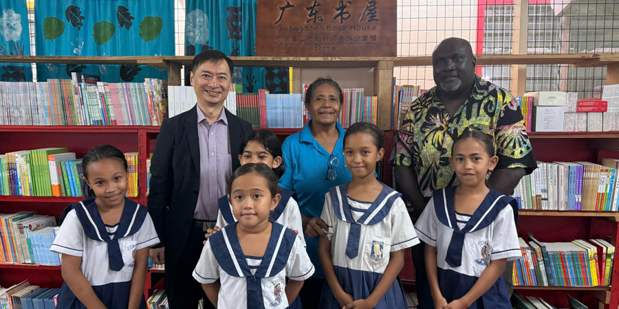 H.E, Weiming, Principal Tahuniara and Minister Leokana posing for a photo in front of the Books collection in the school’s library.
