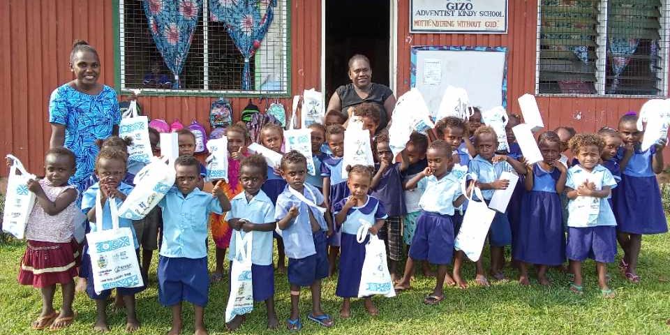 A staff and a member of the awareness team with the students displaying their bags and water bottles