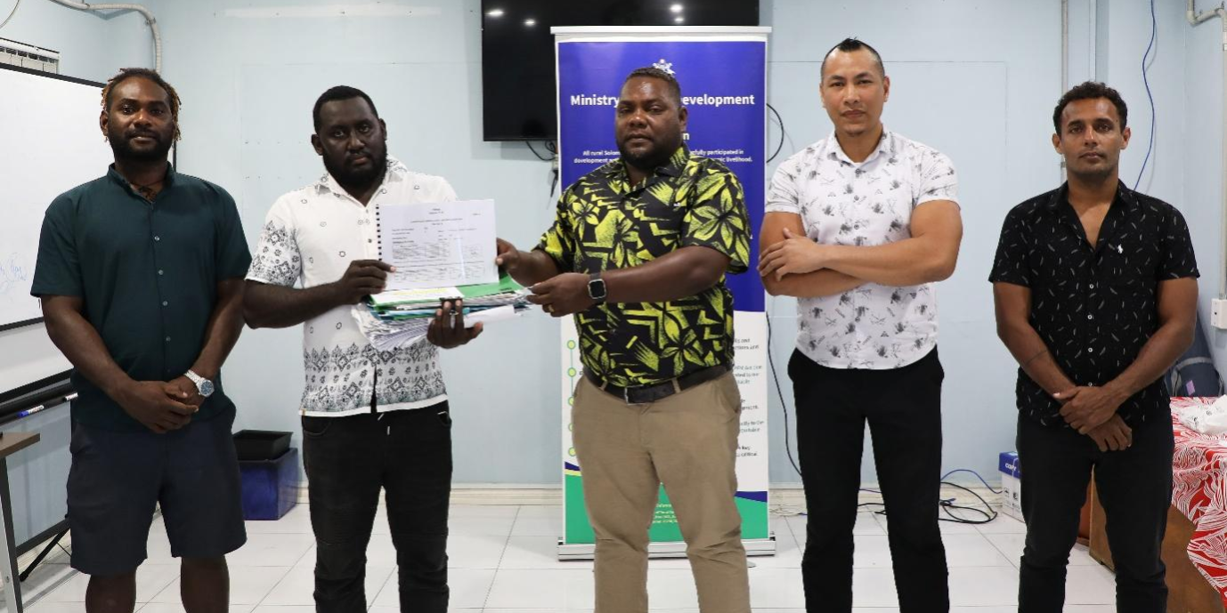 MRD Deputy Secretary Technical (Acting) George Balairamo (centre) receives the report documents from Constituency Accountant Officer (CAO) Victor Bariri