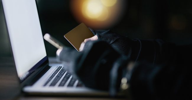 Dont let your credit card out of your sight. Shot of an unidentifiable criminal using a laptop to hack into a credit account.
