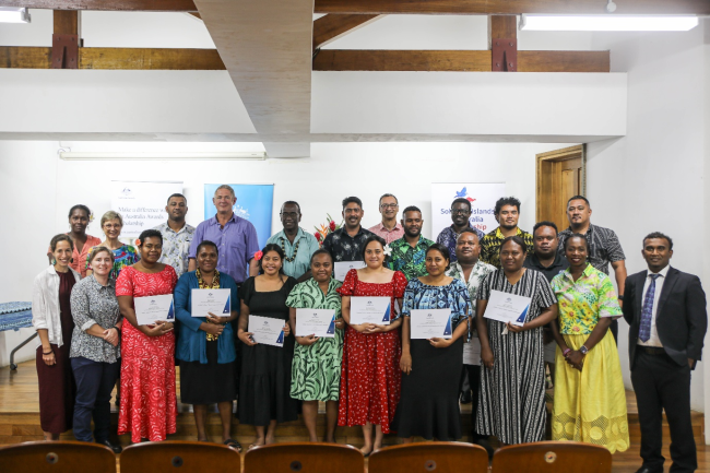 Group photo of the fourteen graduates and officials at the awards ceremony.