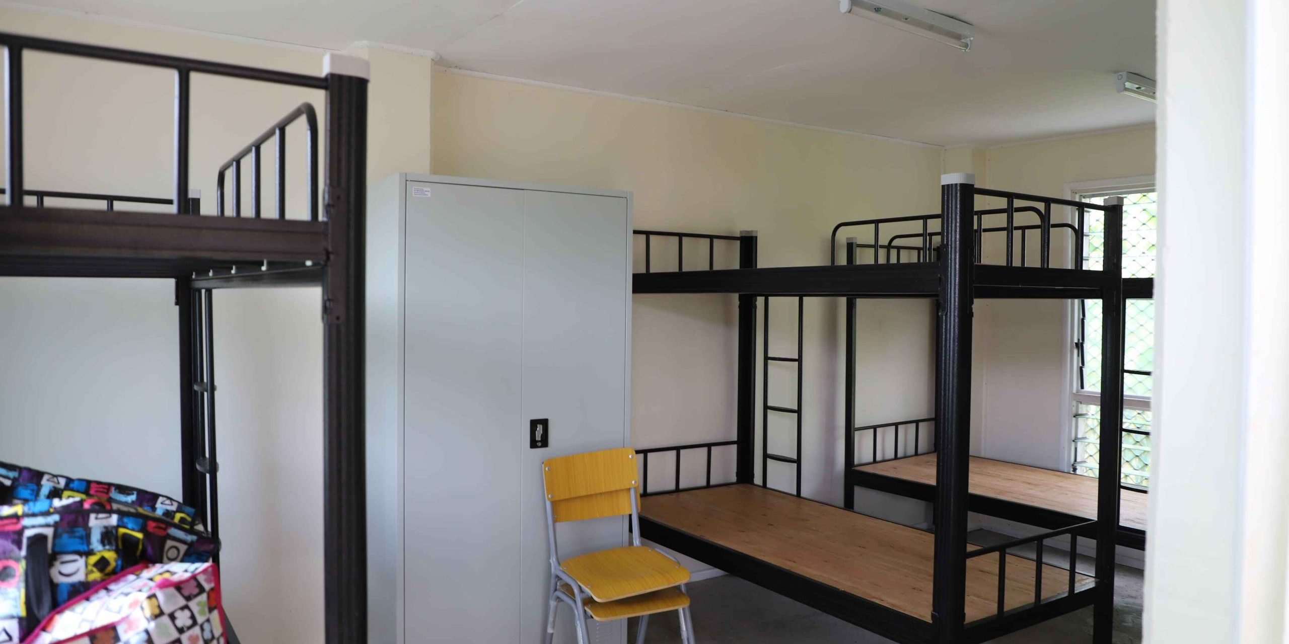 New bunk beds, cabinet, and chairs arranged in the girls’ dormitory at Siro Community High School in Central Province