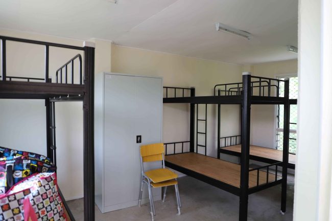 New bunk beds, cabinet, and chairs arranged in the girls’ dormitory at Siro Community High School in Central Province